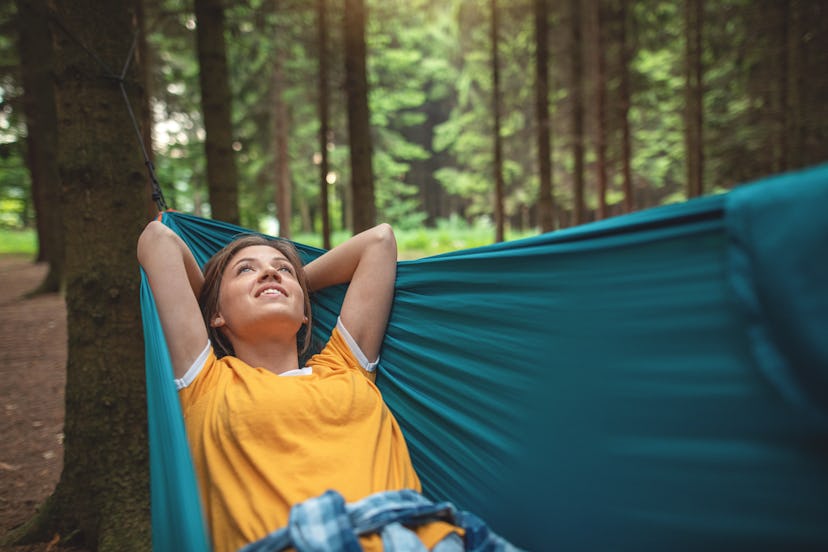 A woman lies in a hammock. Does Hot Weather Make You Lazy? An expert explains the scientific link.