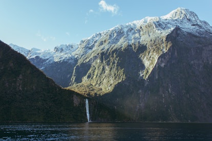 The Milford Sound in New Zealand features a waterfall, ocean, and towering mountains.