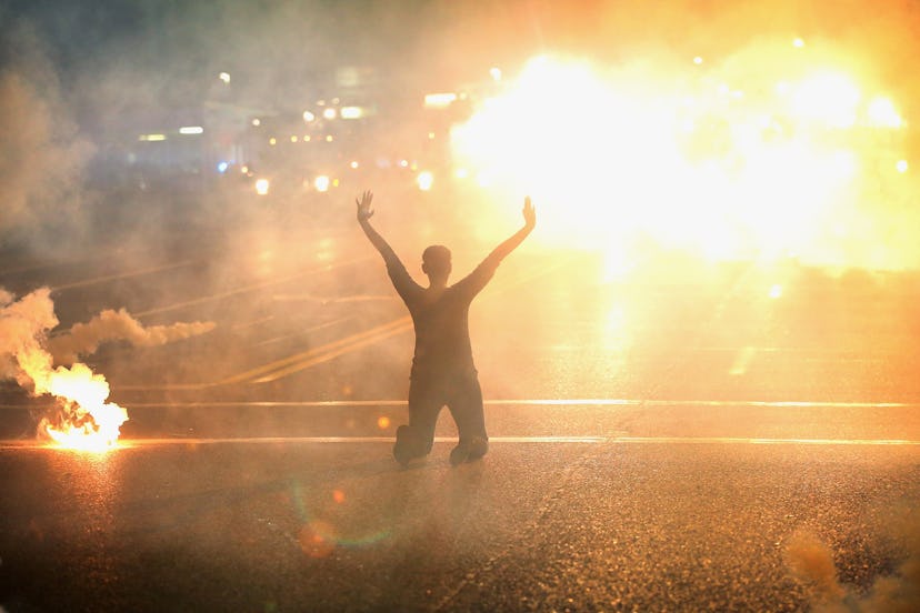 Tear gas reigns down on a woman kneeling in the street with her hands in the air after a demonstrati...
