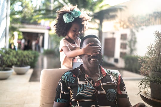 little black girl covering dad's smiling face