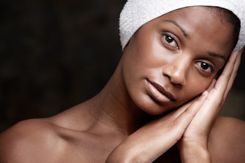 A black woman with a towel on her head, resting her face on her hands