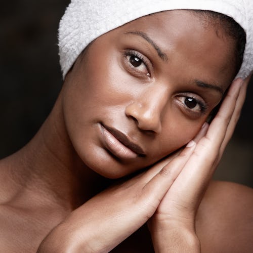 A black woman with a towel on her head, resting her face on her hands