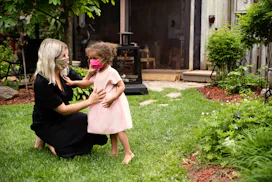 mom wearing a mask fixing mask on little girl