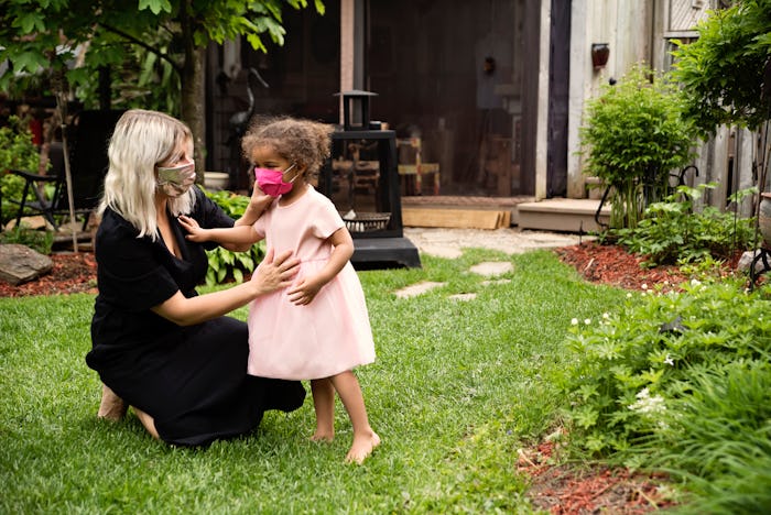 mom wearing a mask fixing mask on little girl