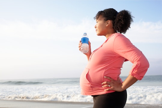 pregnant woman drinking water on beach