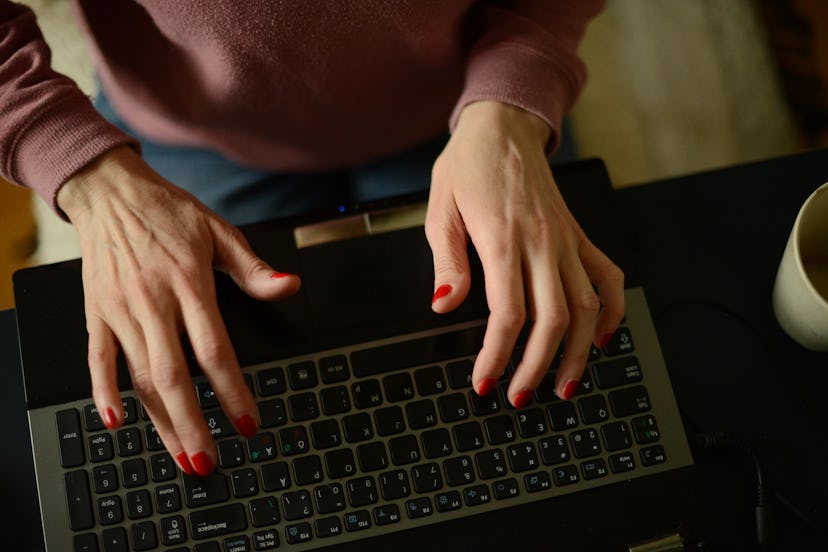 A woman types on a laptop as she contemplates her anxiety about going back to work after coronavirus...