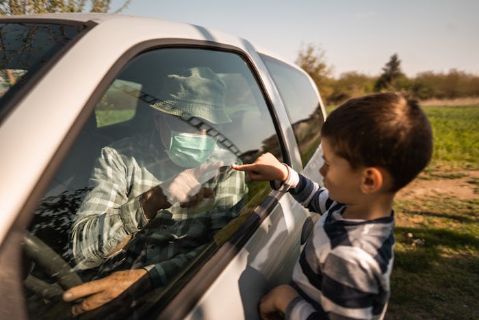 boy and grandfather touching fingers through car window