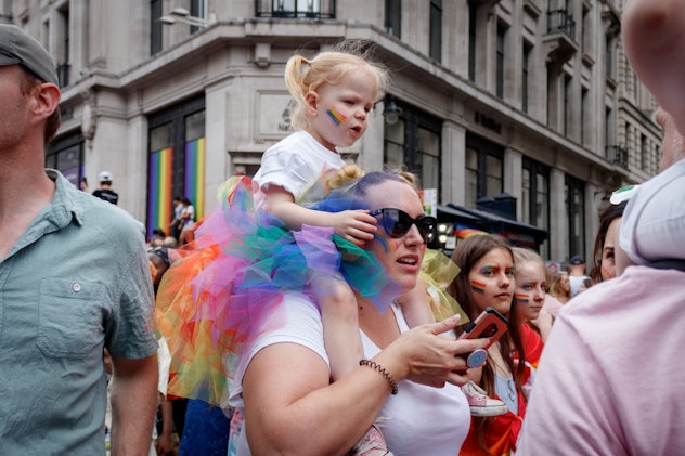 A girl rides on a woman's shoulders at a Pride celebration