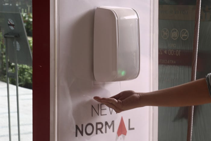 person holding hand under hand sanitizer dispenser