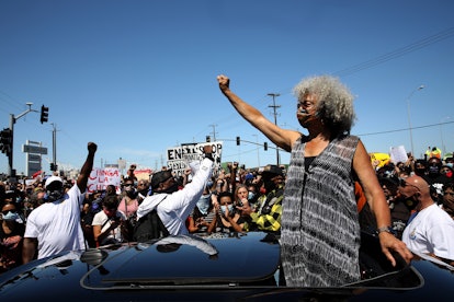 A woman stands above her car at a Black Lives Matter protest. Social distancing is hard at protests,...