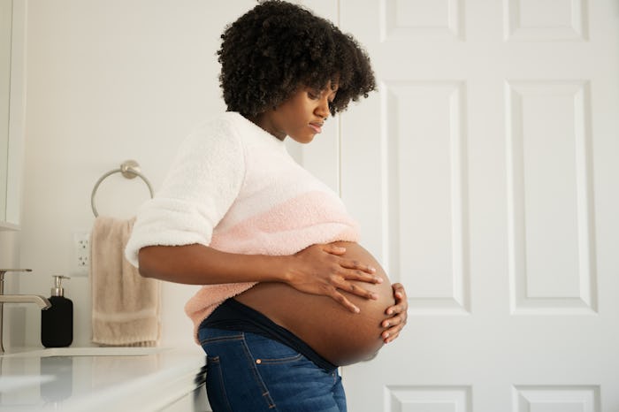 pregnant woman in bathroom holding her bump