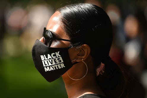 A woman wears a face mask saying Black Lives Matter at a protest. A paper reports that protests didn...