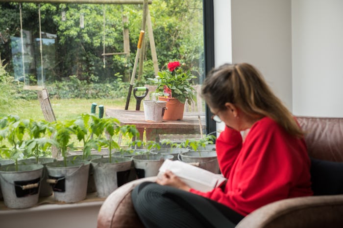 A woman sitting next to a window and reading one of the top LHBTQ books from Goodreads for Pride Mon...