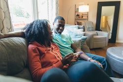 pregnant woman and man sitting on couch with pregnancy test