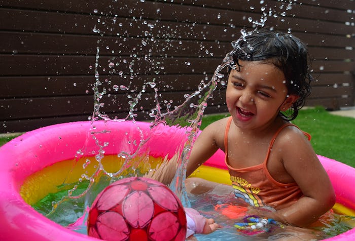 little girl playing in inflatable pool in backyard
