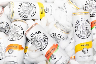 White Claw cans sit in a cooler with ice cubes. 