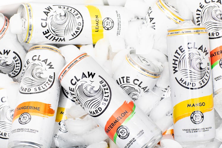 White Claw cans sit in a cooler with ice cubes.