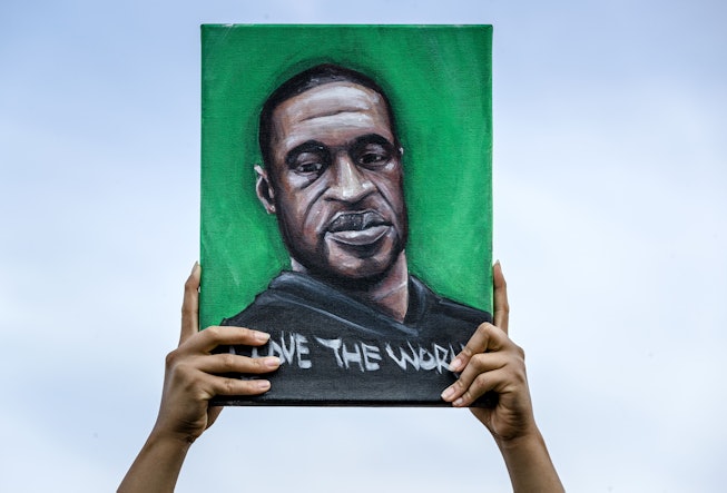 Protesting by holding up a picture of a black man and words "Save the world" under it
