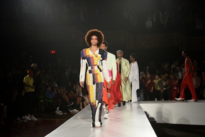 A model in an orange, white and navy check dress walking on front of other model during the digital ...