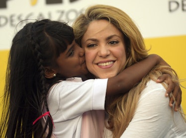 Shakira hugs a child at an event for her Barefoot foundation.