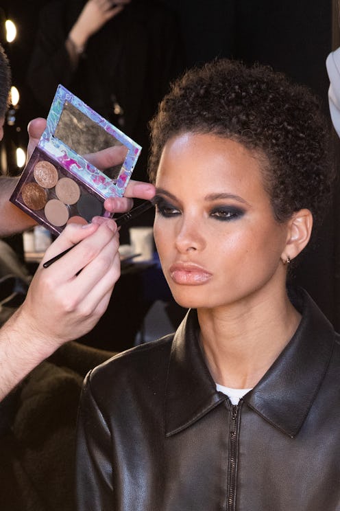 A makeup artist styling a female model with short hair