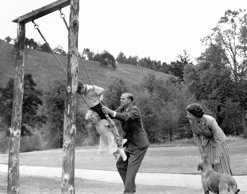 Prince Philip pushes Prince Charles and Princess Anne on a swing in 1955.