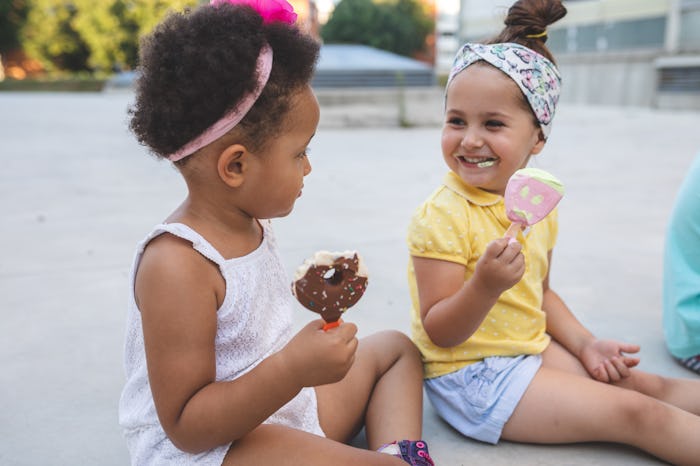 black and white toddler girls eating ice cream at park