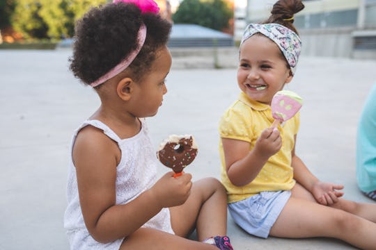 black and white toddler girls eating ice cream at park