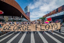 American protestors holding up a sign that says George Floyd, protesting against police brutality to...