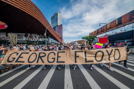 American protestors holding up a sign that says George Floyd, protesting against police brutality to...