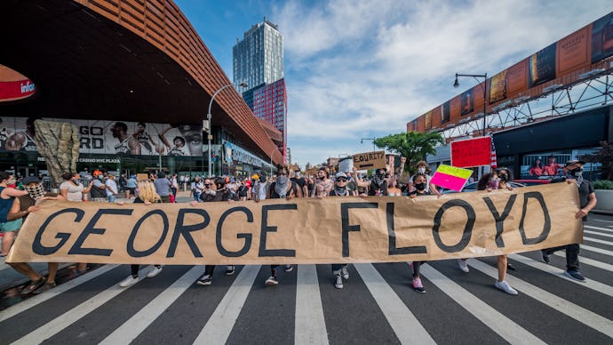 American protestors holding up a sign that says George Floyd, protesting against police brutality to...