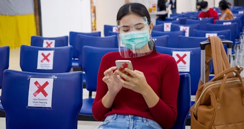 A woman puts on a face shield over her face mask in an airport. Plastic face shields are gaining pop...