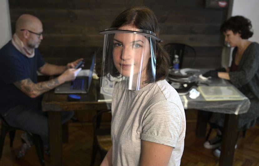 A woman wears a plastic face shield. Face shields may help prevent the spread of coronavirus through...