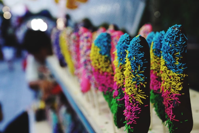 Frozen chocolate dipped bananas with yellow, blue and pink sprinkles lined up in a row 