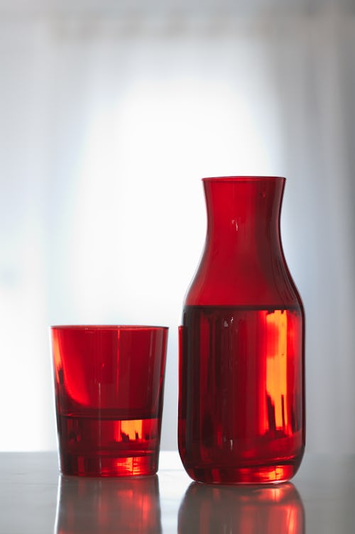 A red glass and a bottle full of liquid