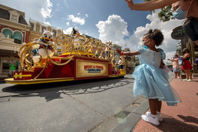 A little girl waves at the Disney cavalcade.