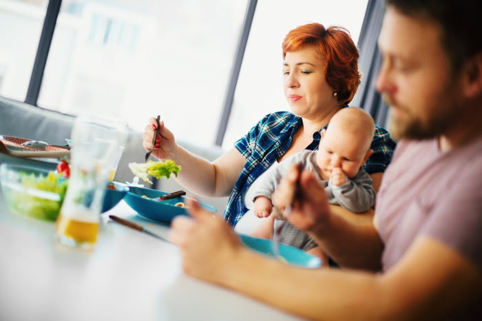 mom holding baby eating salad