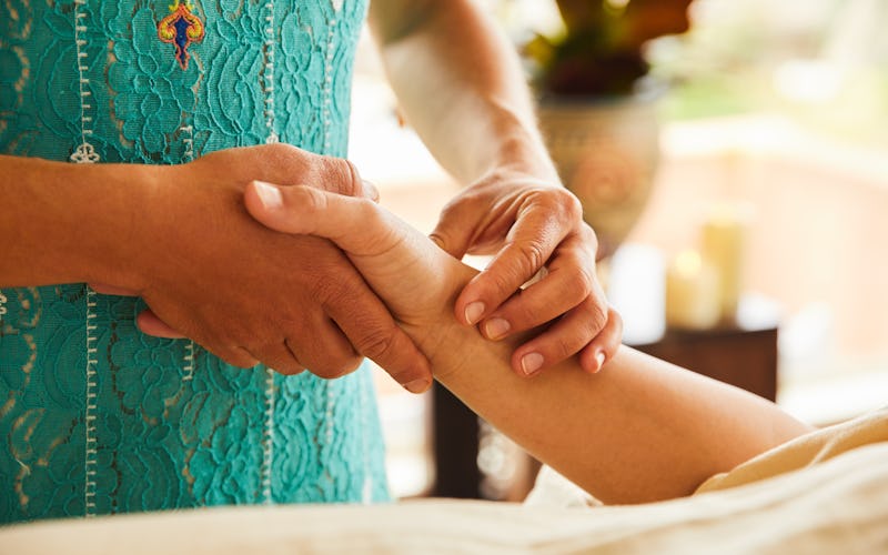 A woman applies reiki on a person's hand. Reiki is used worldwide, but it isn't a cure-all.