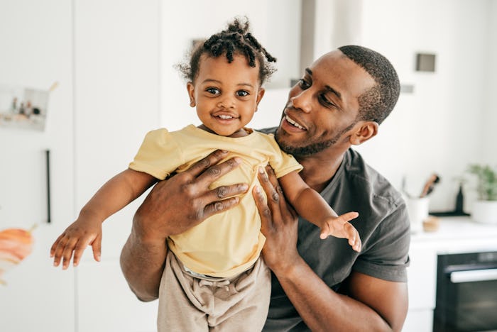 Smiling dad holding his daughter that has a gender neutral baby name inspired by Disney movie