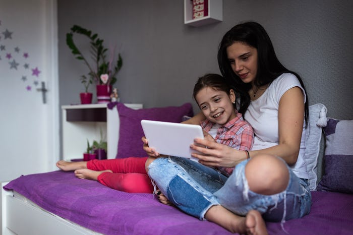 teenage babysitter and little girl sitting on bed
