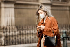 A woman wearing an orange coat and a face mask