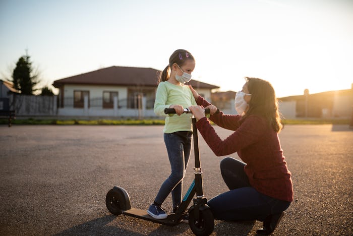 mom and daughter on scooter with face mask