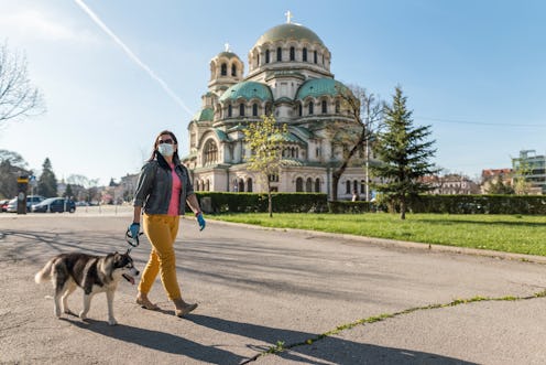 A woman walks her dog while wearing a mask. Fear of outside spaces may become more common during the...