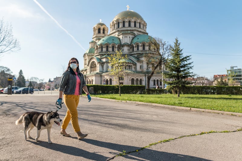 A woman walks her dog while wearing a mask. Fear of outside spaces may become more common during the...