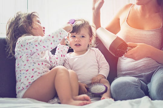 mom and two daughters on couch with hair dryer and brush