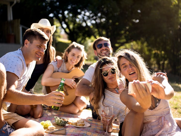 A group of friends pose for an Instagram selfie during a backyard picnic.