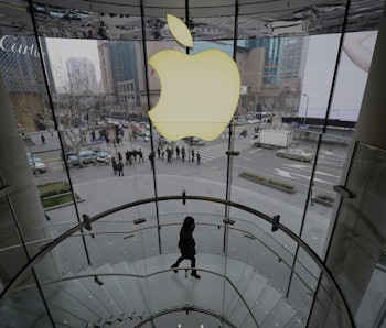 A person is seen walking down the stairs beneath the Apple logo in one of the company’s retail store...