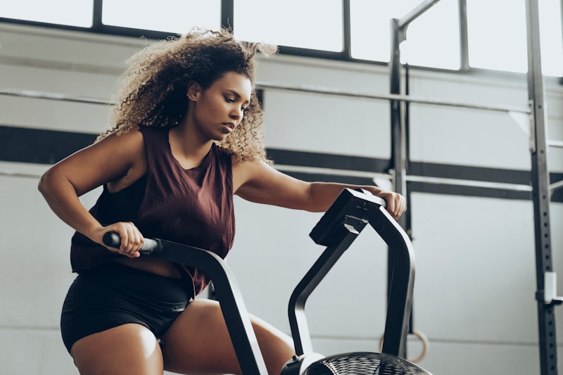 A person with natural curly hair works hard on an elliptical. Motivating yourself to work out by bea...