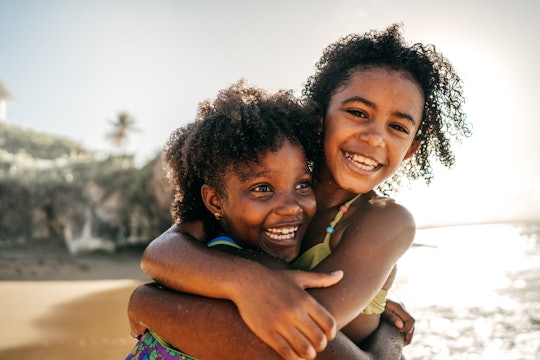 Two kids hugging at a sand beach