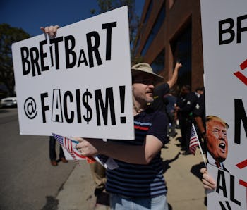 Protestors hold up signs equating Breitbart to fascism and fake news.